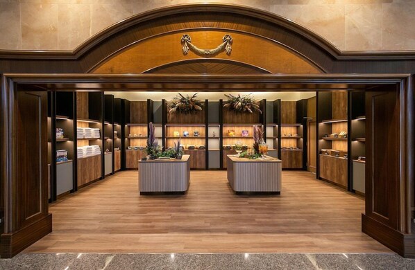 A hotel lobby with a central reception desk, wooden paneling, and decorative plants. - Oriental Hotel Okinawa Resort and Spa (Nago)