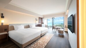 A hotel room with a large bed, a desk, a chair, a TV, and a balcony with a view. - Oriental Hotel Okinawa Resort and Spa (Nago)