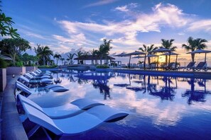 A pool with lounge chairs, umbrellas, and palm trees. - Oriental Hotel Okinawa Resort and Spa (Nago)