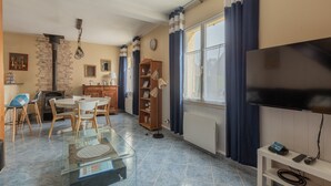 Un salon comprenant un téléviseur, une table en verre, une cheminée, une bibliothèque et un coin repas.