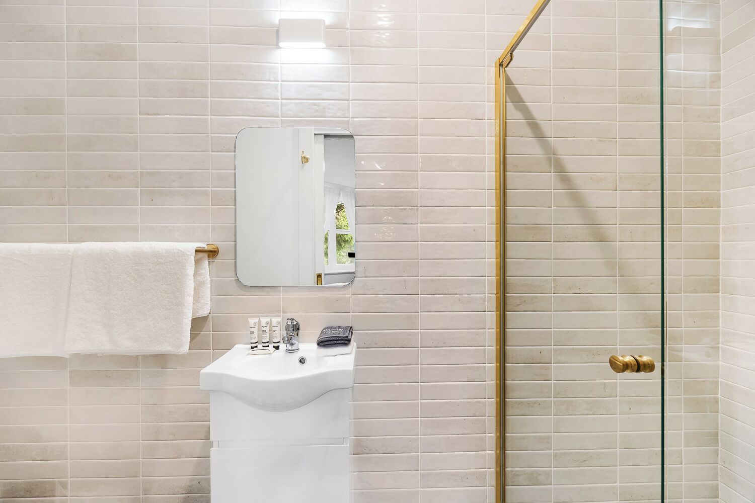 A bathroom with a white sink, a mirror, and a glass shower door.