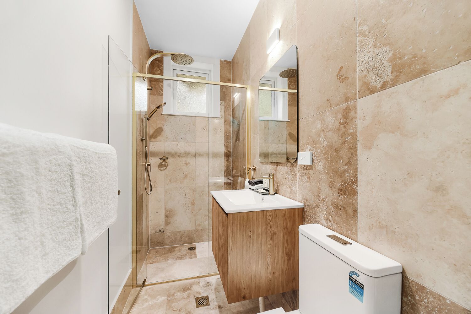 Un bagno con doccia vetrata, un mobile bagno in legno, un lavandino bianco e uno specchio.