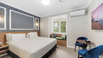Une chambre d’hôtel moderne équipée d’un lit, d’un bureau, d’une chaise, d’une fenêtre avec vue et d’un appareil de climatisation.