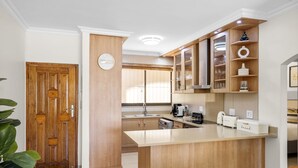 A modern kitchen with wooden cabinets, a central island, and a built-in oven. - Kiahuna 2 (uMhlanga)