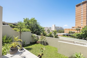 A rooftop garden with potted plants, a palm tree, and a view of surrounding buildings. - Kiahuna 2 (uMhlanga)