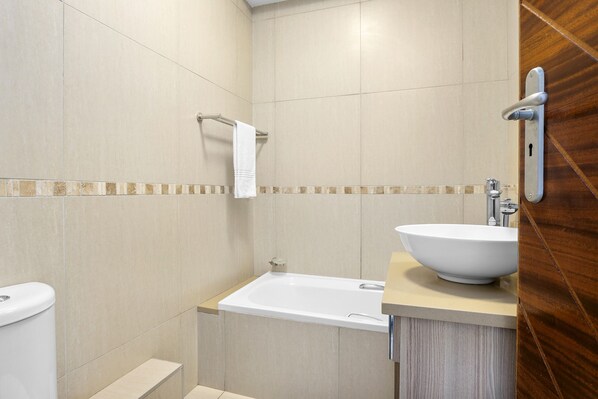 A modern bathroom with a bathtub, a toilet, and a sink. - Kiahuna 2 (uMhlanga)