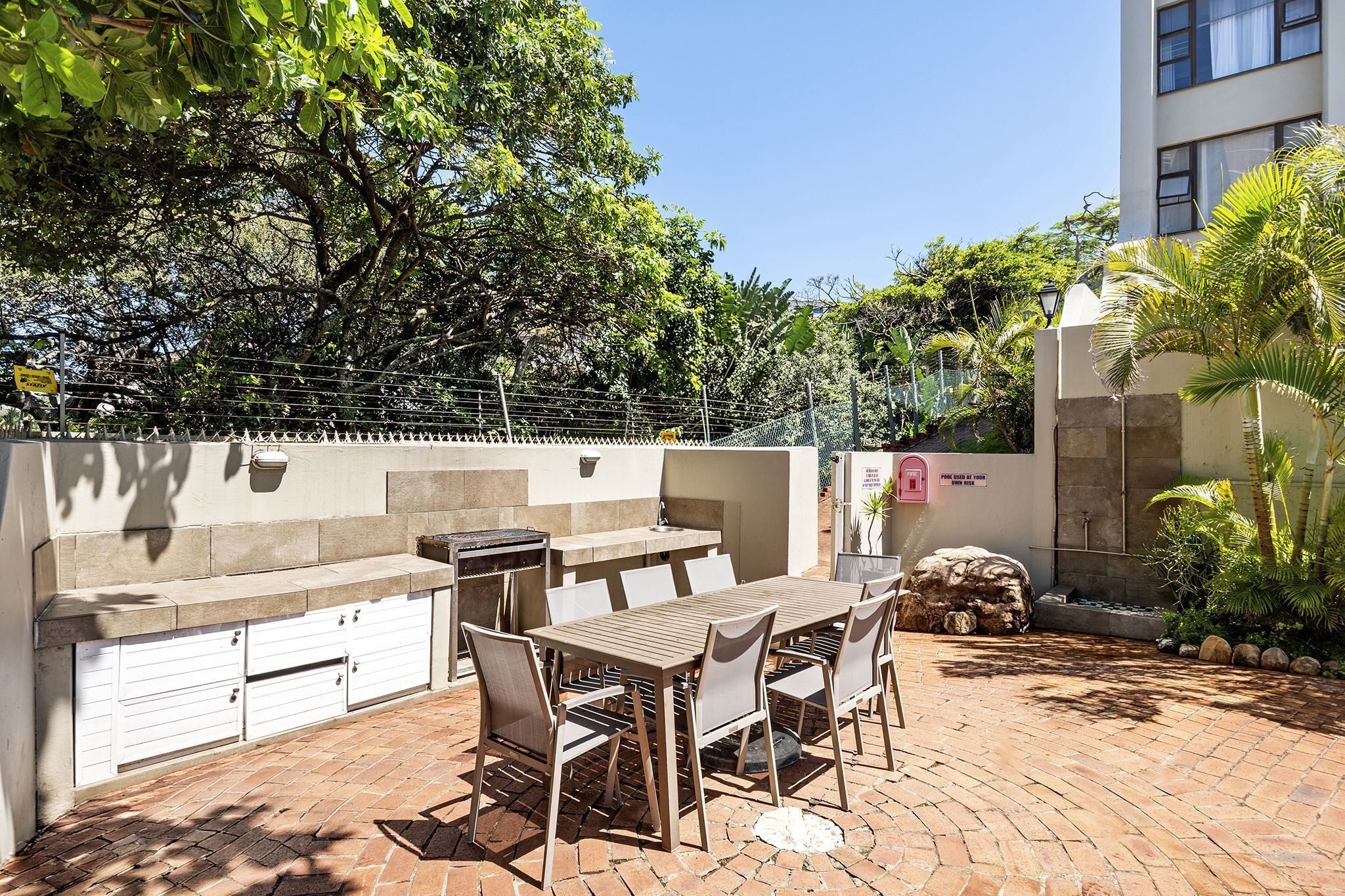 An outdoor patio with a barbecue grill, dining table, and chairs.