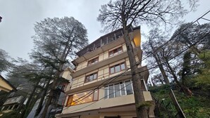 A multi-story building with a garage entrance, surrounded by trees. - Kavin Uphar - The Mall (Shimla)