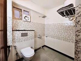 A bathroom with a toilet, a shower, a towel rack, and a window.