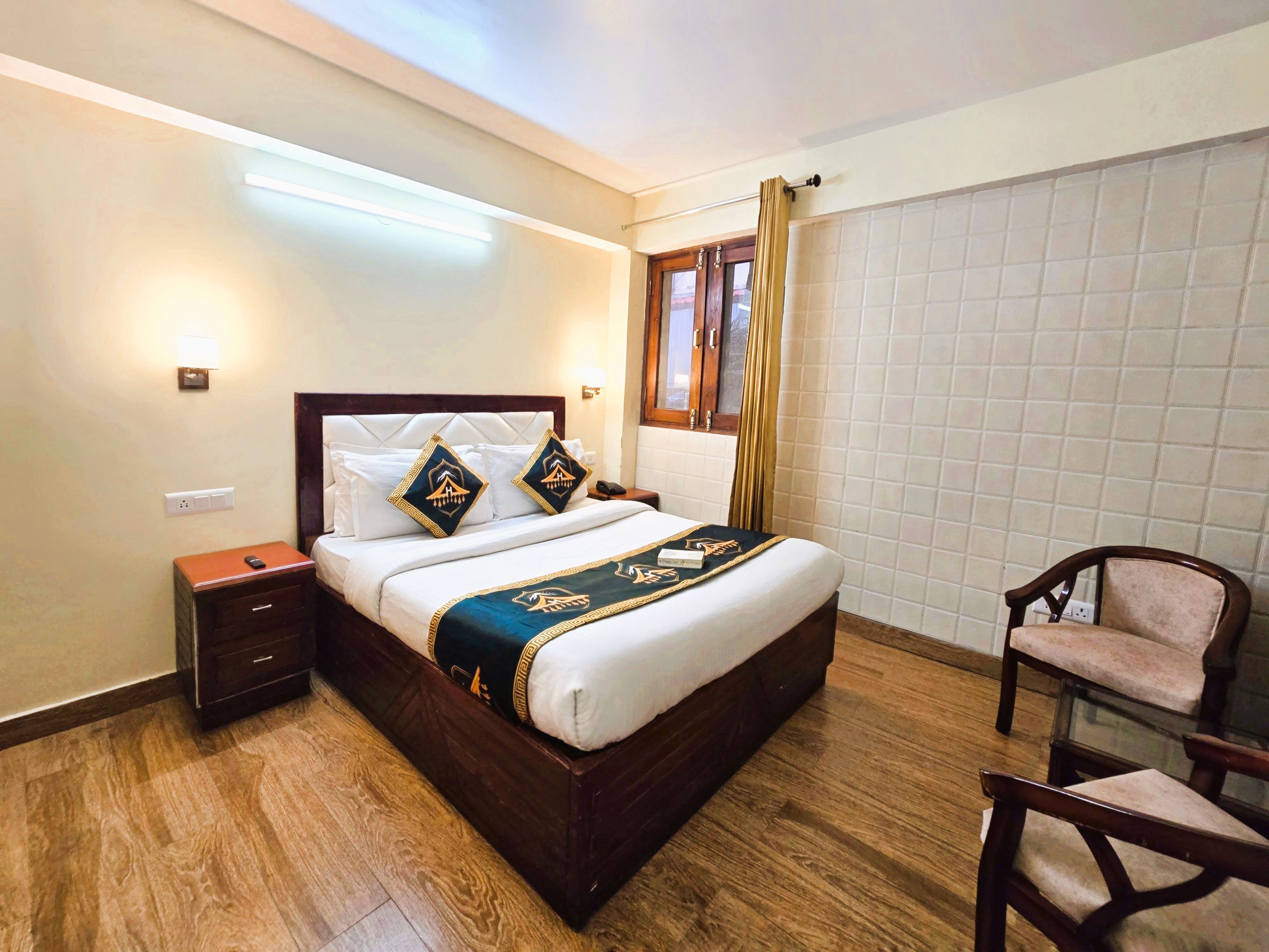 A hotel room with a large bed, bedside tables, a chair, and a window with curtains.