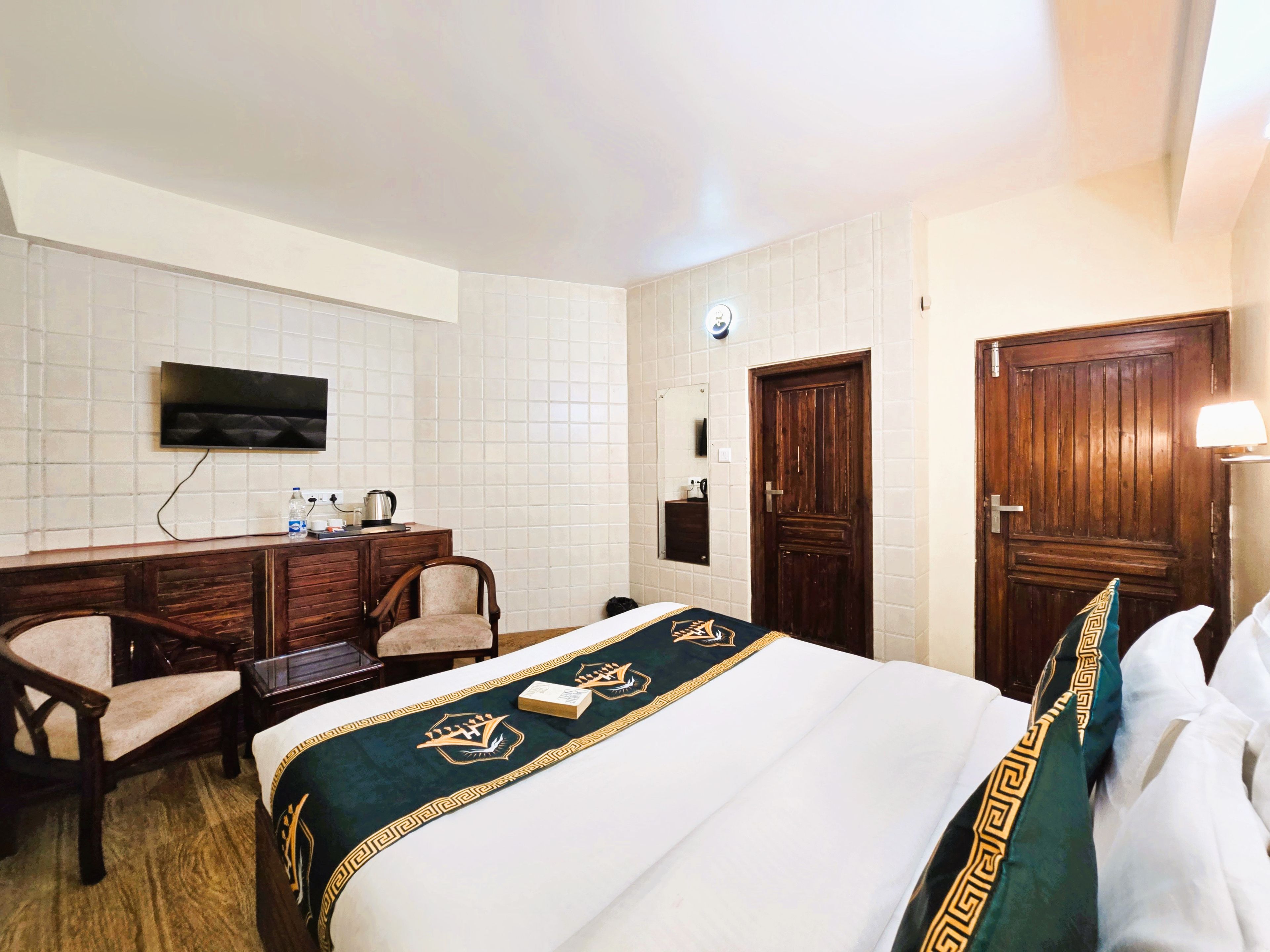 Una habitación de hotel con una cama, un escritorio, una silla, un televisor y un armario.