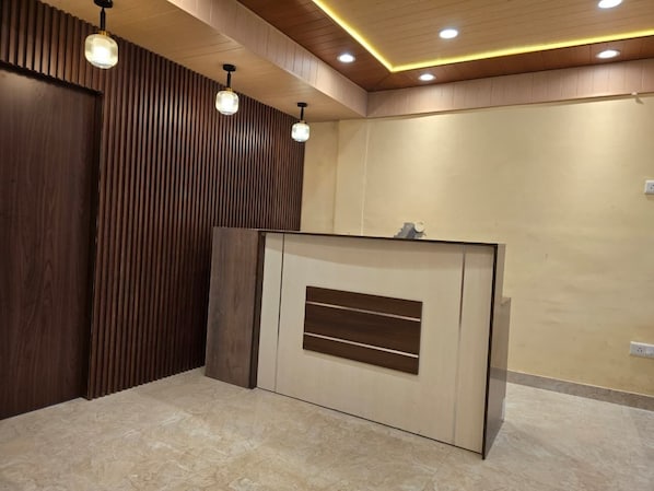 A reception area with a wooden panel wall, a reception desk, and pendant lighting. - Kavin Uphar - The Mall (Shimla)