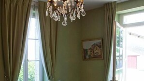 A dining area with a table set for four, a chandelier, and a painting on the wall. - Domaine Rollan de by (Bégadan)