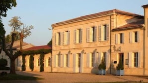 A two-story building with a symmetrical facade, multiple windows, and a central entrance. - Domaine Rollan de by (Bégadan)