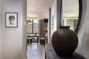 A hallway with a large vase, a framed picture, and a view of the outdoors. - Art Apartment I - Table Mountain View Pool Nomad (Cape Town)