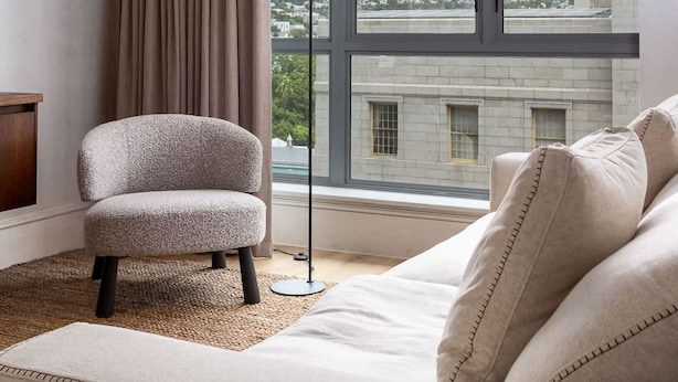 Ett modernt rum med ett stort fönster, en soffa, en fåtölj och en lampa.