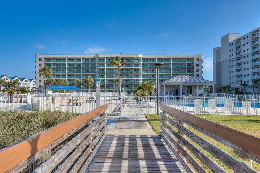 A hotel with a pool area, a wooden boardwalk, and a large building with multiple balconies.