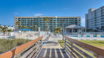 A hotel with a pool area, a wooden boardwalk, and a large building with multiple balconies.