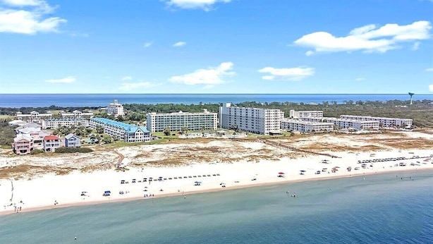 Een kusthotel met meerdere gebouwen, een strand en een heldere lucht.