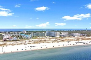 A coastal hotel with multiple buildings, a beach, and a clear sky. - Cozy Resort Studio | 6 Pools • Tennis • Beach Access (Gulf Shores)
