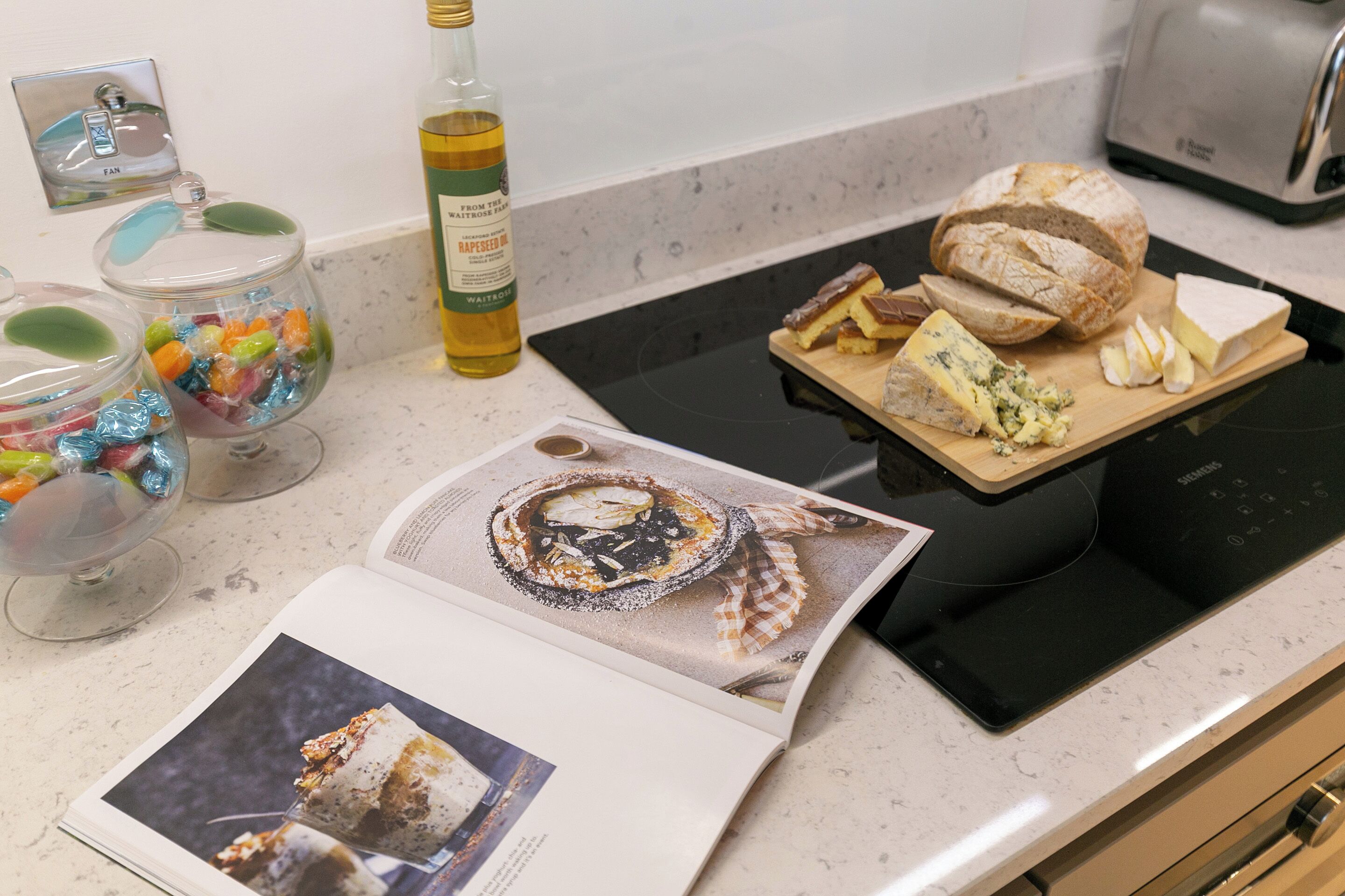 A kitchen counter with a loaf of bread, a bottle of wine, and a magazine.