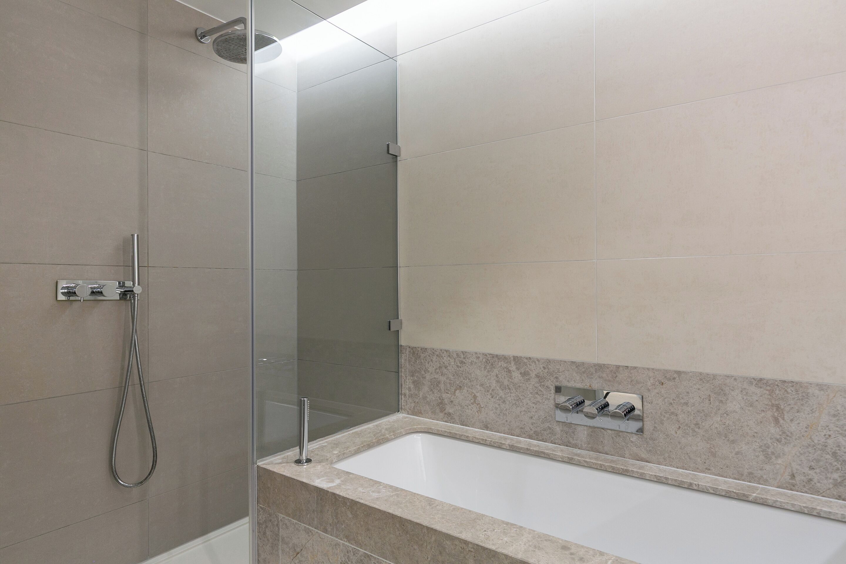 A bathroom with a shower, a bathtub, and a mirror.