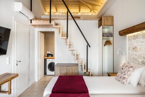 Ein Schlafzimmer mit einem Bett, einer roten Decke, einer Holzbank, einer Waschmaschine und einer Treppe.