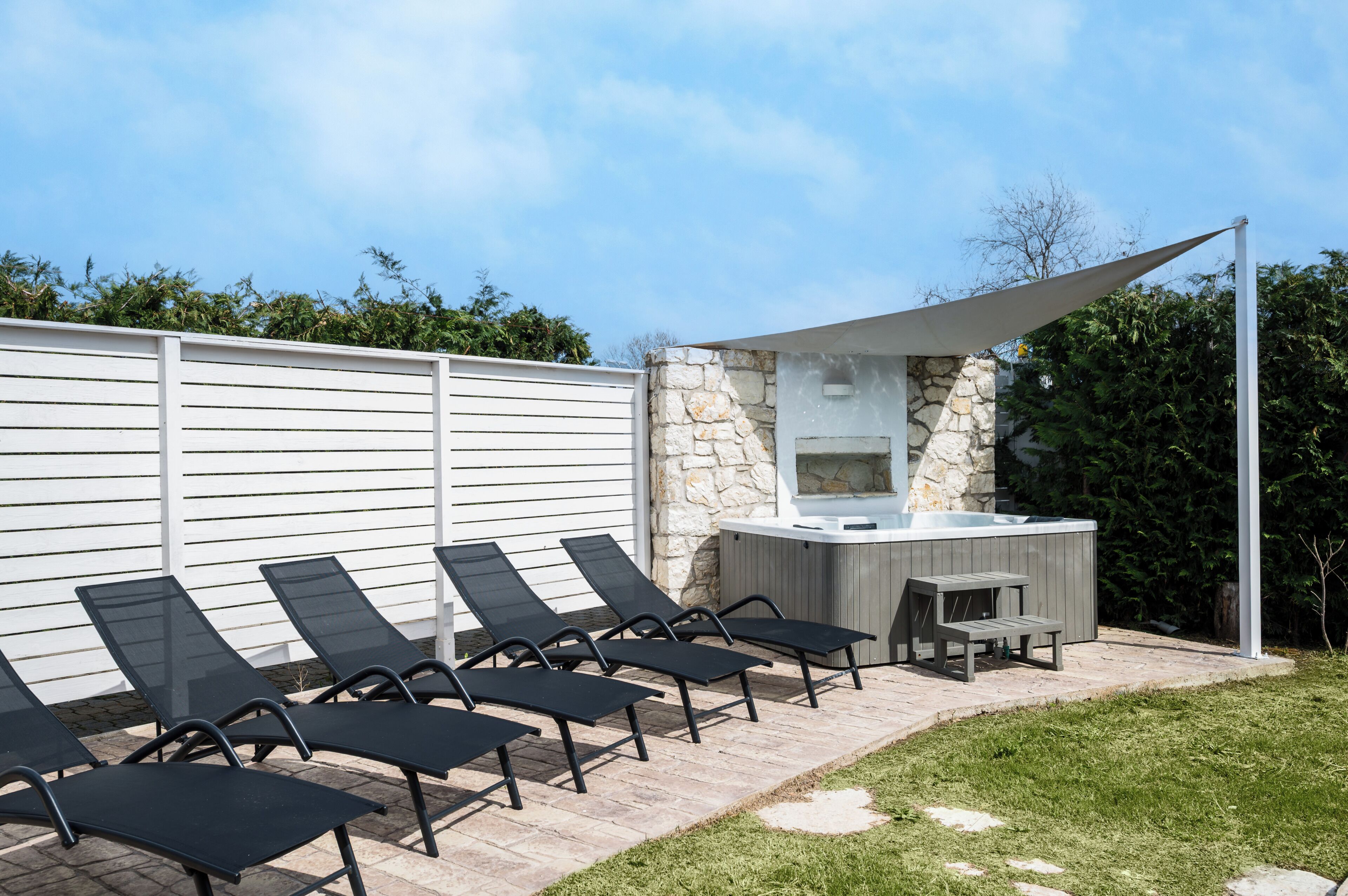 Eine Terrasse mit Sitzgelegenheit im Freien, einer Steinmauer und einem Whirlpool.