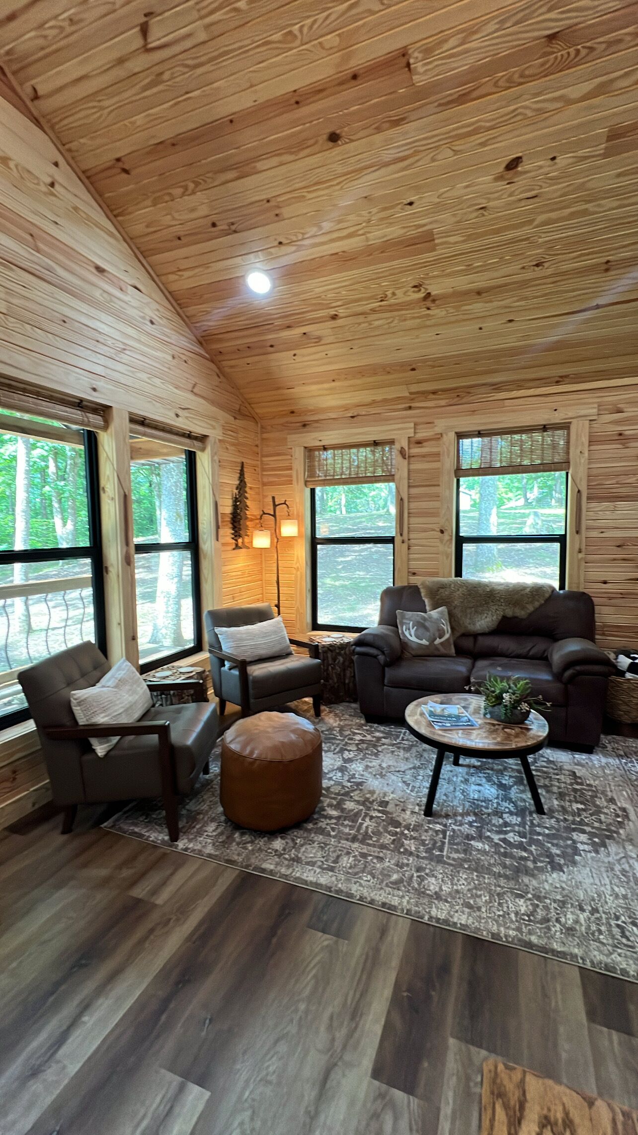 A wooden interior with a sofa, chairs, and a coffee table.