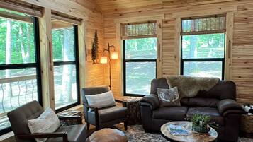 A wooden interior with a sofa, chairs, and a coffee table.