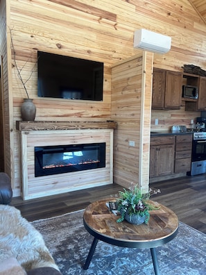 A wooden interior with a fireplace, a television, and a kitchen area.