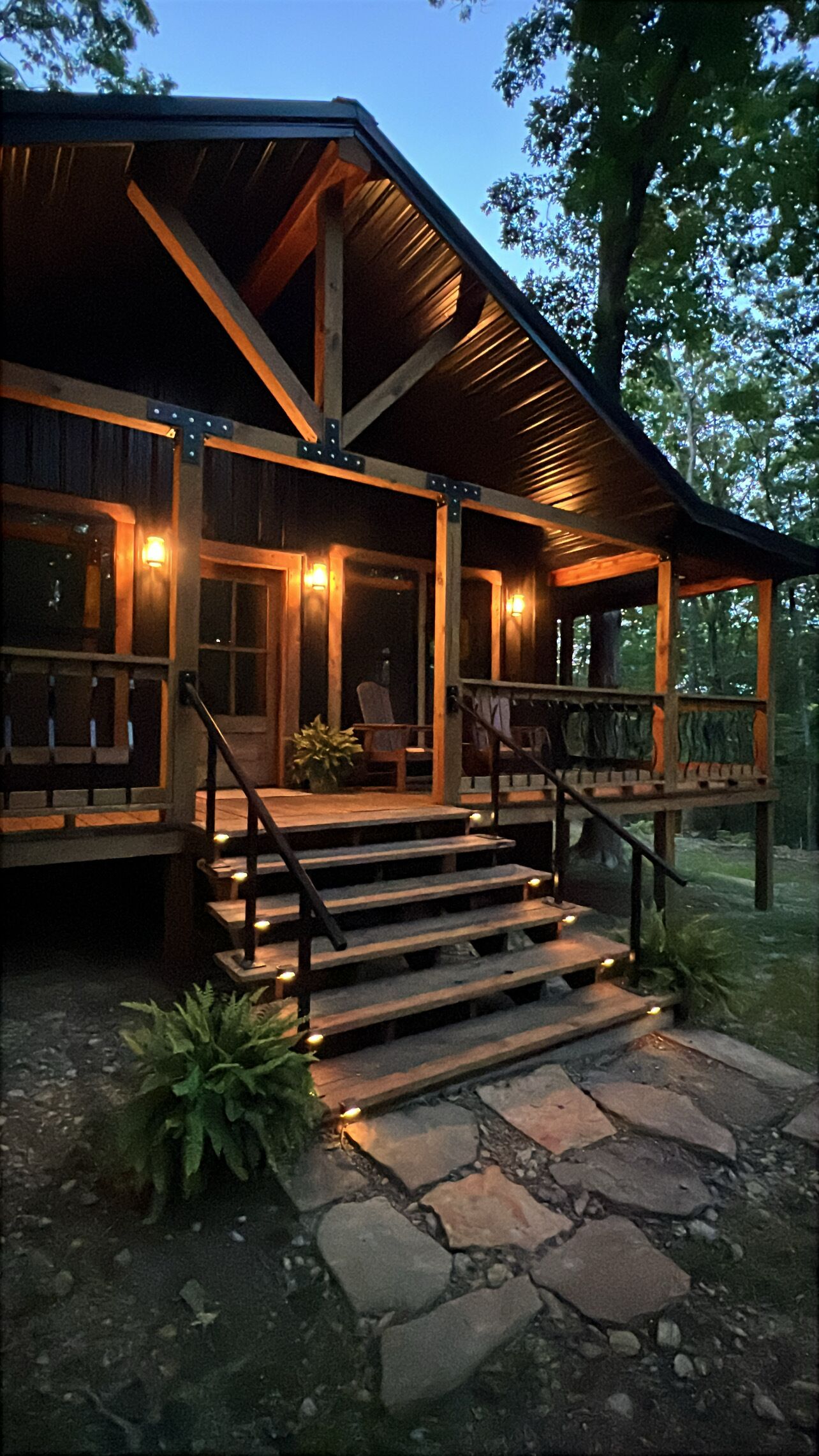 Une cabane en bois dotée d’une véranda, d’un escalier en pierre et d’une balustrade.