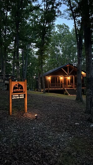 A cabin with a porch, surrounded by trees, and a sign indicating it is Timber Ridge.