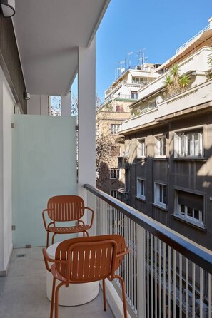 A balcony with two chairs, a white wall, and a view of neighboring buildings. - The signature Suite in Kolonaki / luxury 1BR apt (Athens)