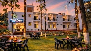 Un hôtel à plusieurs étages doté d’une terrasse, d’un chemin en pierre et d’une enseigne indiquant « Park Palace, maison d’hôtes de luxe ».
