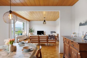 A dining area with a wooden table, chairs, and a view of the outdoors. - Lotterberg Holiday Apartment (Gudensberg)