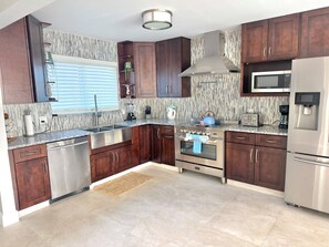 A modern kitchen with dark wooden cabinets, stainless steel appliances, a microwave, and a built-in oven. - Sanibel Retreat - Walk to the Beach! (sanibel)
