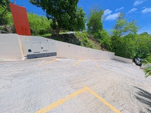 Ein Parkplatz mit gelben Markierungen, einer Betonwand und einer roten Struktur.