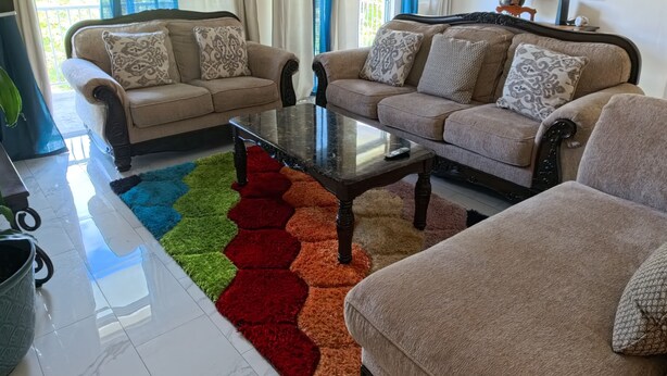 A living room with two sofas, a coffee table, and a colorful rug. - Serene Family - 4Bed/4Bath Private Ensuite (Cruz Bay)