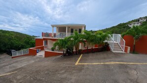 A building with a balcony, a staircase, and a parking area. - Serene Family - 4Bed/4Bath Private Ensuite (Cruz Bay)