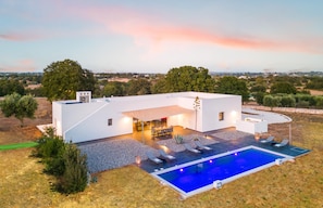 Ein modernes Haus mit Swimmingpool, Sitzgelegenheiten im Freien und Blick auf die Landschaft.