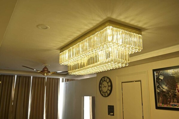 Un candelabro, un ventilador de techo, un reloj y una puerta en una habitación.