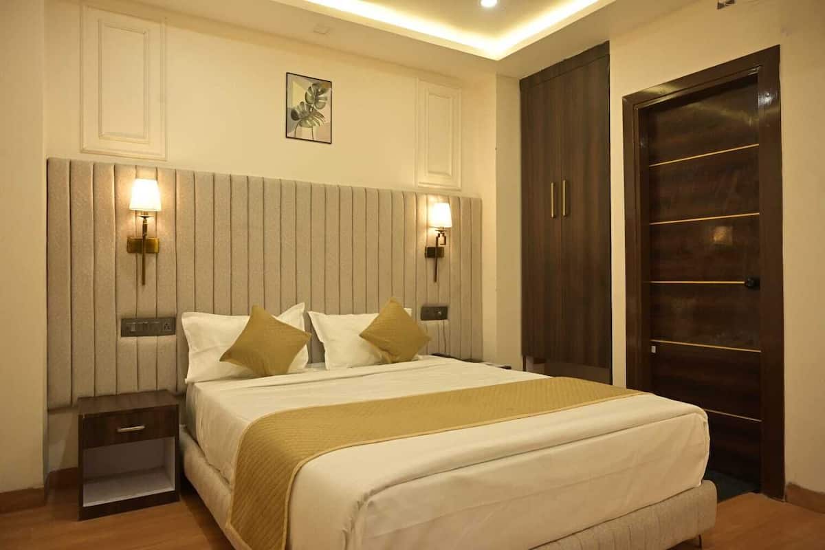 A hotel room with a bed, bedside tables, wall-mounted lights, a wardrobe, and a door.