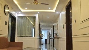 Un pasillo de hotel con ventilador de techo, iluminación empotrada, un sofá y una mesa de vidrio.