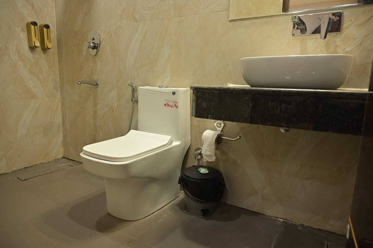 Ein Badezimmer mit Toilette, Waschbecken, Toilettenpapierhalter und Mülleimer.