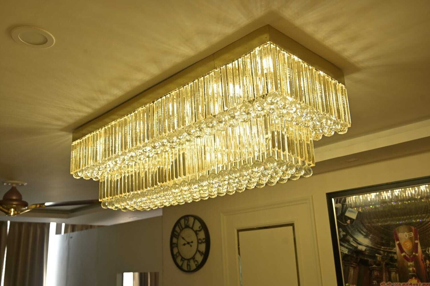 Un lustre à plusieurs niveaux, orné de cristaux, et une horloge murale.