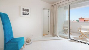 A room with a blue chair, a glass door leading to a balcony, a framed picture on the wall, and a small decorative item on the floor. - Villa Pia by Nova Villas (Vabriga)