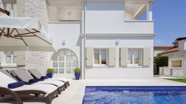 A two-story white building with a swimming pool, outdoor seating, and a clear blue sky. - Villa Pia by Nova Villas (Vabriga)