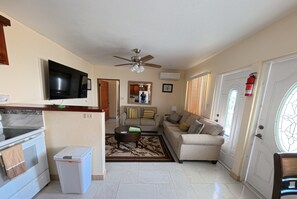 Ein Wohnzimmer mit Fernseher, Sofa, Couchtisch und Deckenventilator.