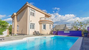 Un edificio de dos pisos con piscina, balcón y un área cubierta.